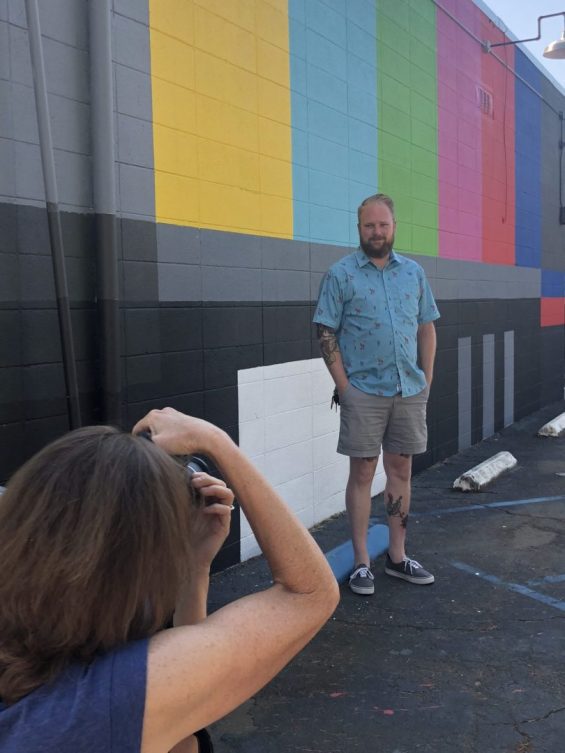 Person taking a photograph in front of mural