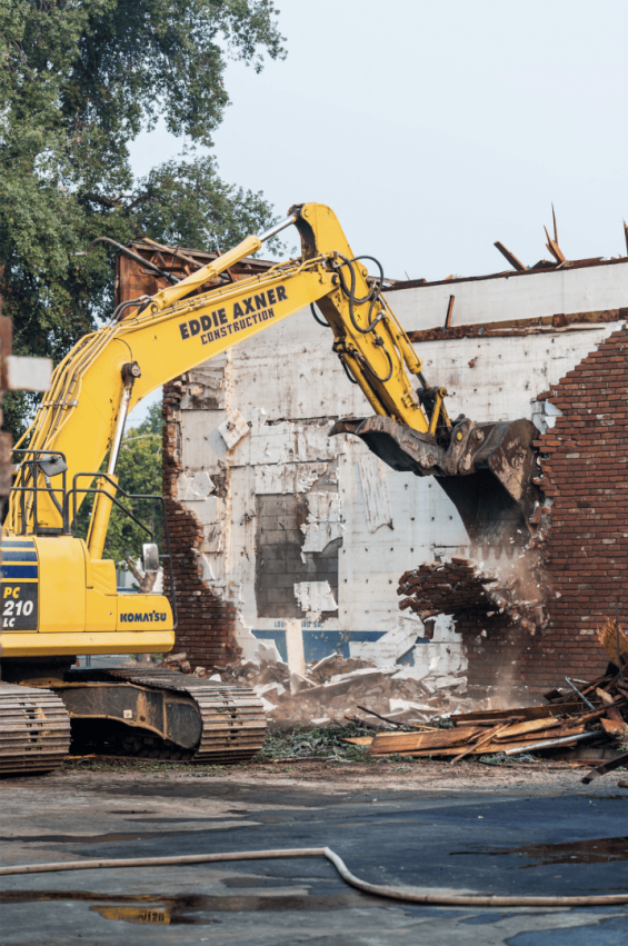 Excavator demolishing brick building